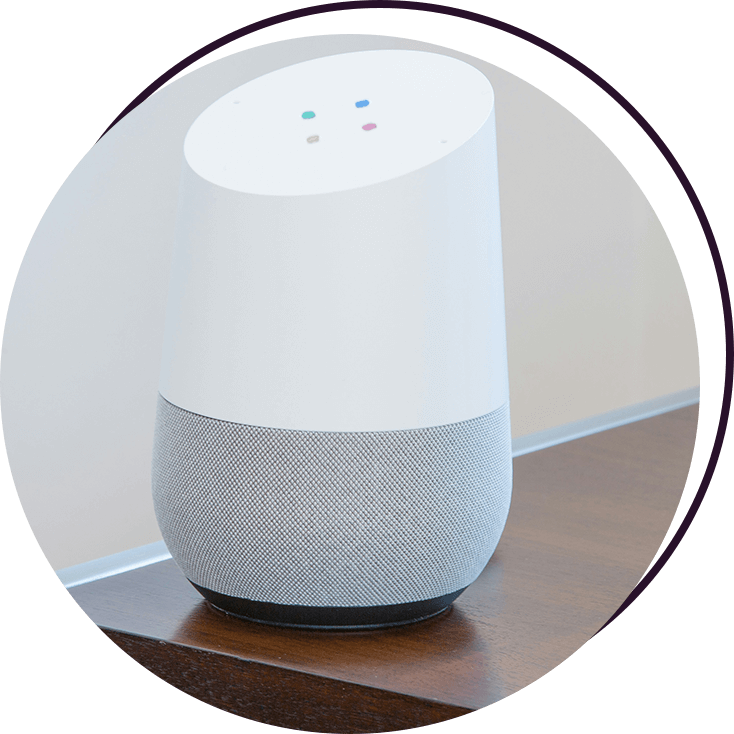 A white google home sitting on top of a wooden table.