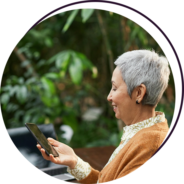 A woman is holding her tablet in the garden.